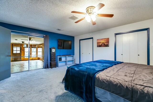 carpeted bedroom featuring ceiling fan, a textured ceiling, and two closets