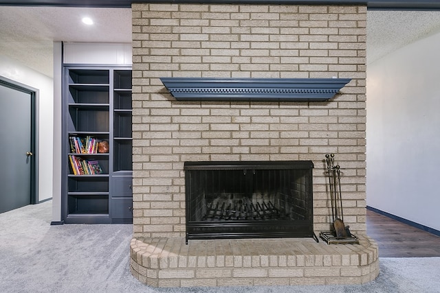 details featuring a brick fireplace, built in features, a textured ceiling, and carpet