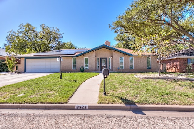 single story home featuring a garage, a front yard, and solar panels