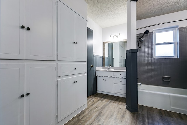 bathroom featuring hardwood / wood-style flooring, vanity, tiled shower / bath combo, and a textured ceiling