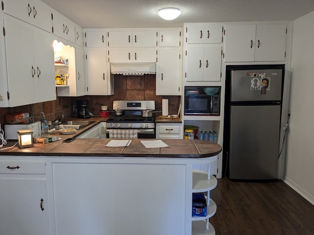 kitchen featuring stainless steel appliances, kitchen peninsula, and white cabinets