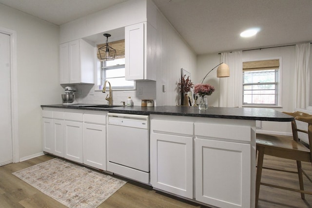 kitchen featuring white dishwasher, decorative light fixtures, and white cabinets