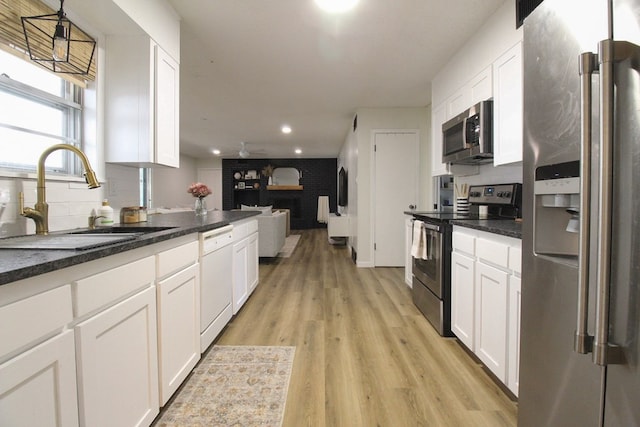 kitchen with sink, light hardwood / wood-style flooring, hanging light fixtures, appliances with stainless steel finishes, and white cabinets