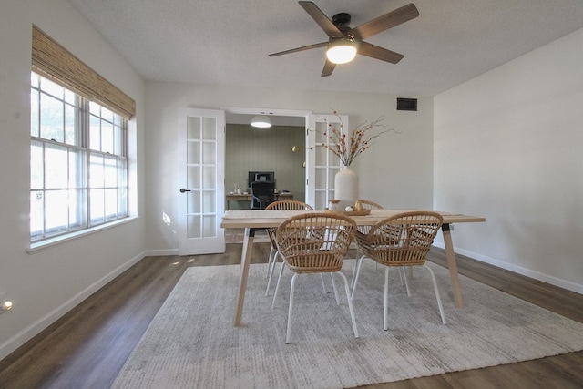 dining area featuring ceiling fan, dark wood-type flooring, french doors, and a textured ceiling