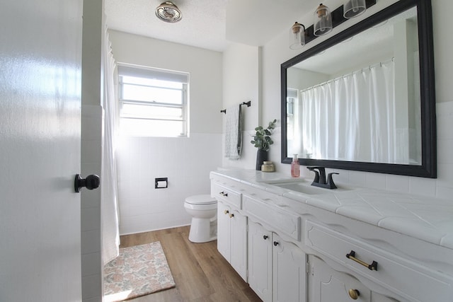 bathroom with tile walls, vanity, hardwood / wood-style flooring, and toilet