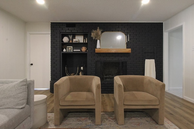 living room featuring hardwood / wood-style flooring, a fireplace, and a textured ceiling