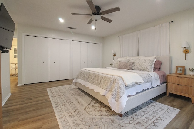 bedroom featuring two closets, wood-type flooring, and ceiling fan