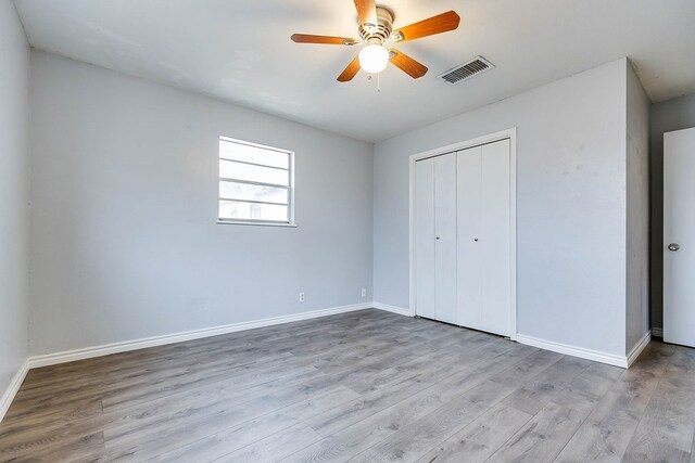 unfurnished bedroom with light hardwood / wood-style flooring, a closet, and ceiling fan