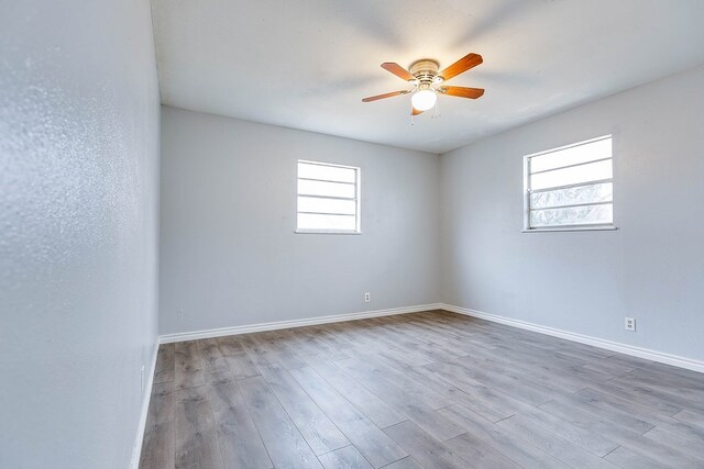 empty room with ceiling fan, plenty of natural light, and light hardwood / wood-style flooring