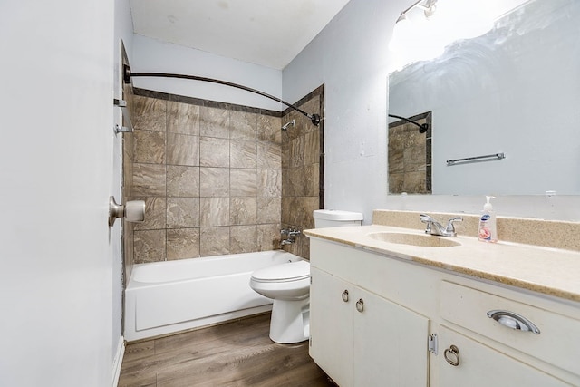 full bathroom with wood-type flooring, toilet, tiled shower / bath combo, and vanity