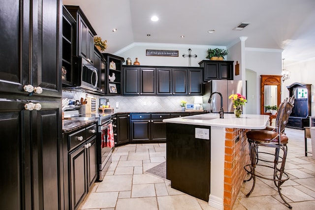 6023 Warwick Dr, San Angelo, TX 76904 - kitchen featuring appliances with stainless steel finishes, open shelves, backsplash, ornamental molding, and a center island with sink