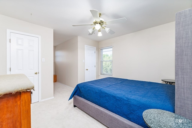 bedroom with a ceiling fan, light carpet, and baseboards