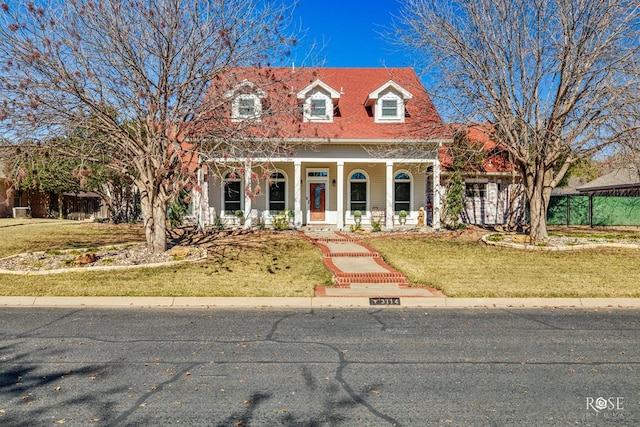 cape cod-style house featuring covered porch and a front lawn