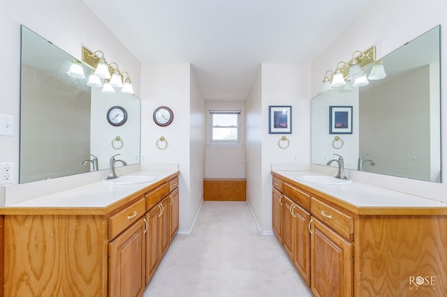 bathroom featuring baseboards, a sink, and two vanities