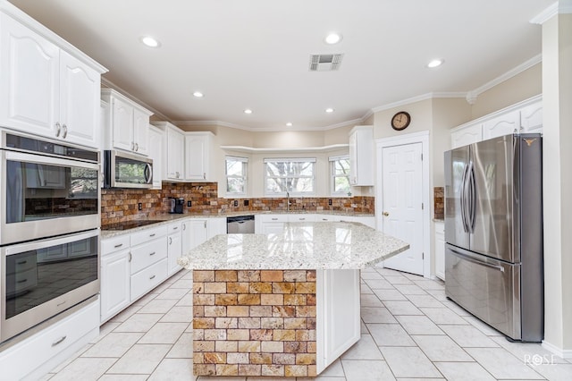 kitchen featuring white cabinets, visible vents, stainless steel appliances, and backsplash