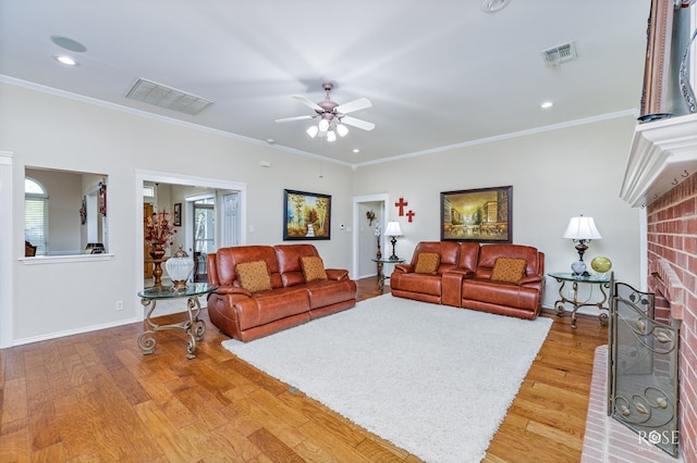 living area with a ceiling fan, light wood finished floors, a fireplace, and visible vents