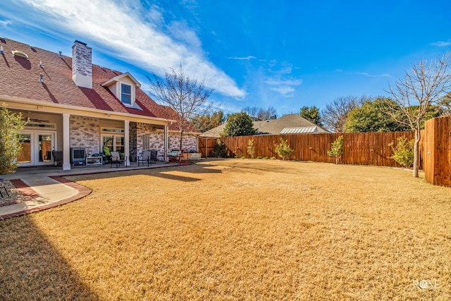 view of yard with a fenced backyard, a patio, and french doors