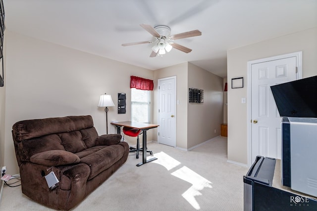 sitting room featuring light colored carpet, baseboards, and a ceiling fan