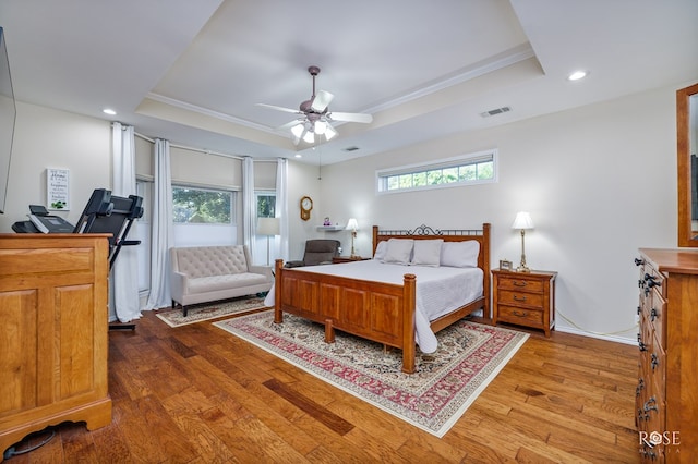 bedroom featuring recessed lighting, a tray ceiling, and wood finished floors
