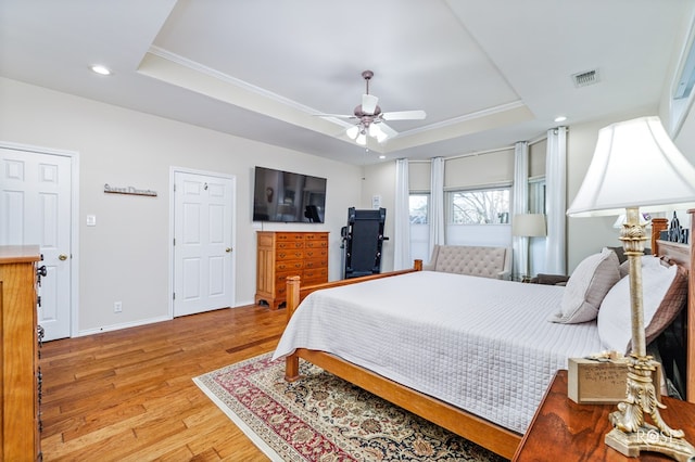 bedroom with visible vents, light wood-style flooring, baseboards, recessed lighting, and a raised ceiling