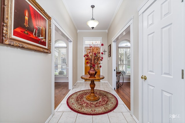 entrance foyer featuring light tile patterned floors, crown molding, and baseboards