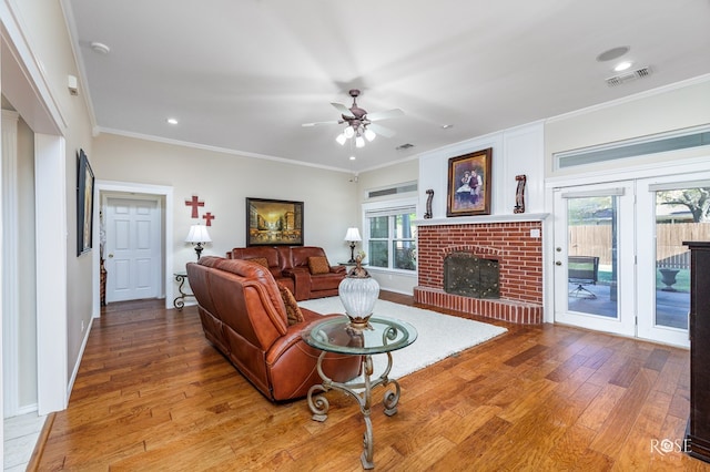living area with visible vents, ornamental molding, light wood-type flooring, and a fireplace