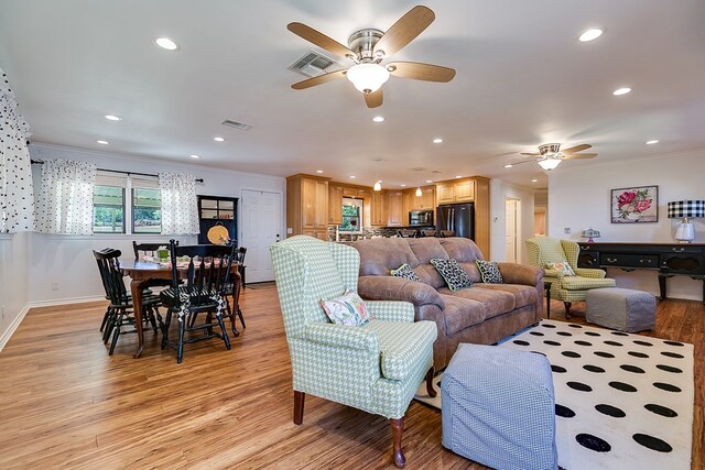 living room featuring ornamental molding, ceiling fan, and light hardwood / wood-style flooring