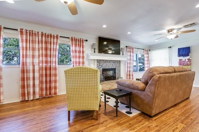 living room featuring ceiling fan, crown molding, light hardwood / wood-style flooring, and a healthy amount of sunlight