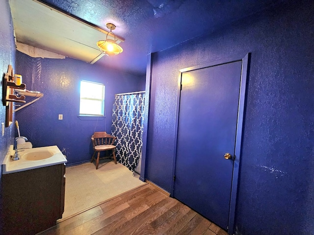 bathroom with hardwood / wood-style flooring, vanity, a shower with curtain, and a textured ceiling