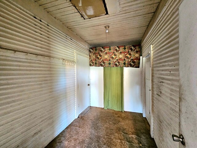 carpeted spare room with wood ceiling and wooden walls