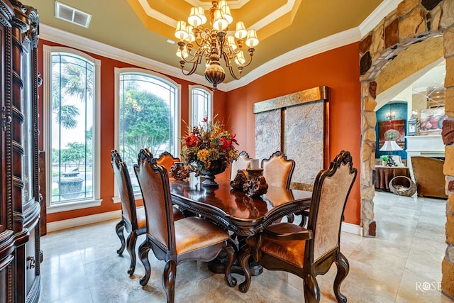 dining space featuring a tray ceiling, a chandelier, crown molding, and a wealth of natural light