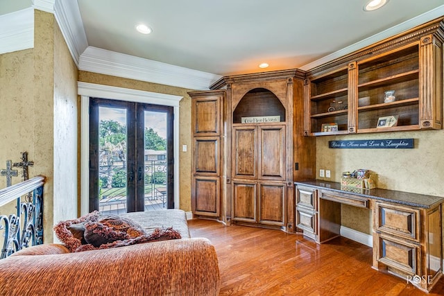 interior space with french doors, crown molding, built in desk, and wood-type flooring