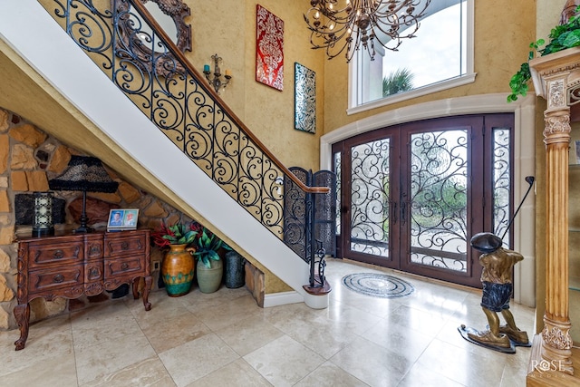 entrance foyer with a high ceiling, french doors, and a notable chandelier