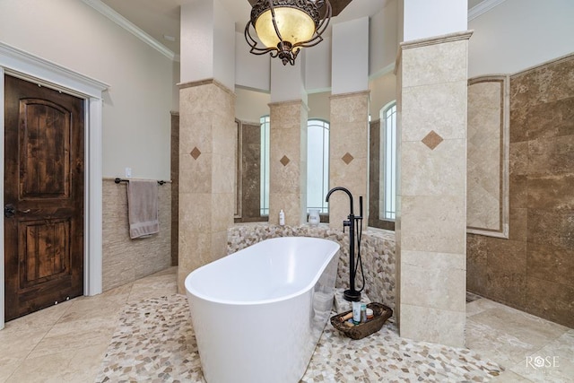 bathroom with independent shower and bath, decorative columns, tile walls, a notable chandelier, and crown molding