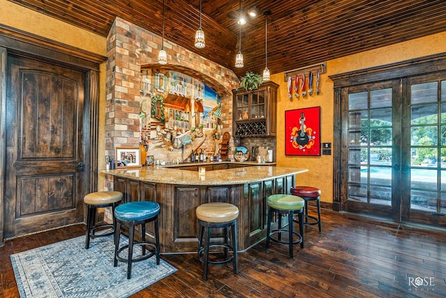 bar with dark wood-type flooring, wooden ceiling, light stone countertops, and decorative light fixtures