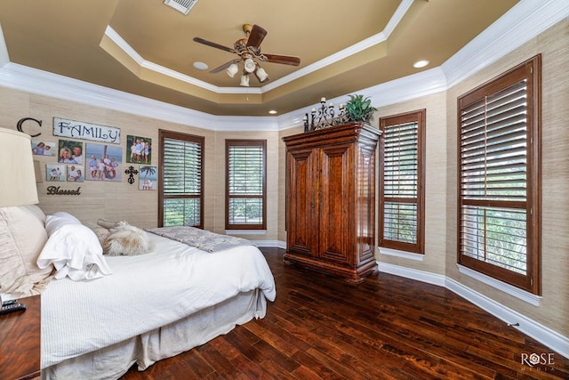 bedroom with a tray ceiling, crown molding, dark hardwood / wood-style floors, and multiple windows