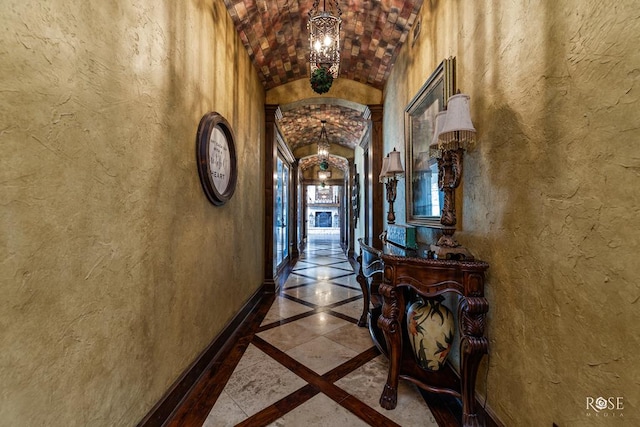 corridor featuring brick ceiling, lofted ceiling, and a notable chandelier