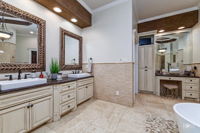 bathroom with a bathtub, vanity, tile walls, and ornamental molding