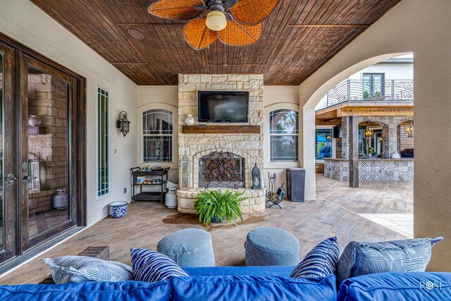 view of patio with ceiling fan and an outdoor living space with a fireplace