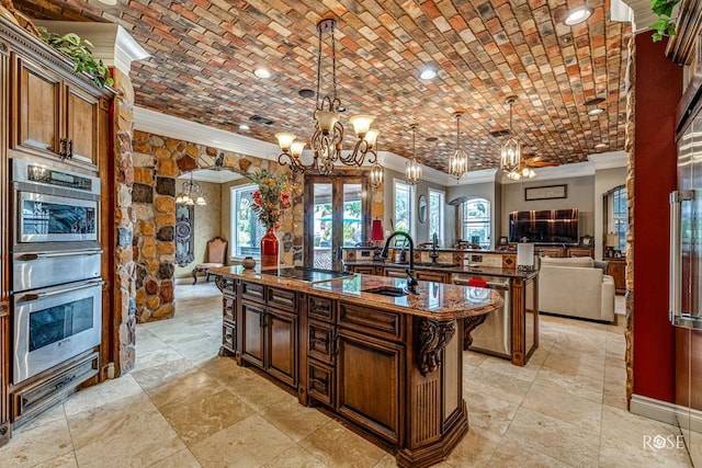 kitchen featuring a center island with sink, decorative light fixtures, an inviting chandelier, sink, and appliances with stainless steel finishes