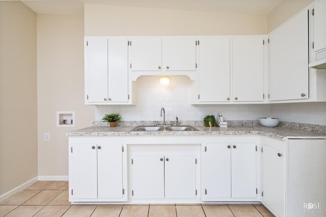 kitchen featuring white cabinetry, sink, light stone countertops, and light tile patterned flooring