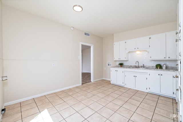 kitchen featuring light tile patterned flooring, sink, white cabinetry, light stone counters, and backsplash