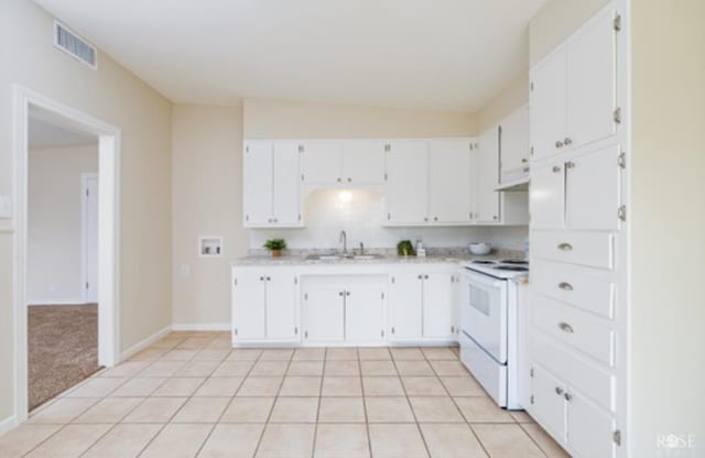 kitchen featuring light colored carpet, white electric range, sink, and white cabinets