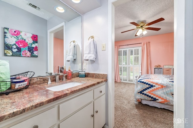 3210 Briargrove Ln, San Angelo, TX 76904 - ensuite bathroom featuring visible vents, vanity, ceiling fan, connected bathroom, and a textured ceiling