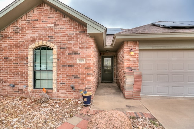 doorway to property with a garage and solar panels