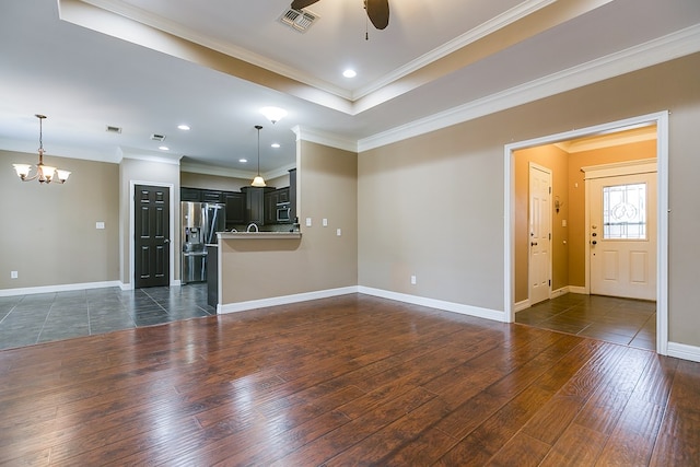 unfurnished living room with crown molding, dark wood-type flooring, a raised ceiling, and ceiling fan with notable chandelier