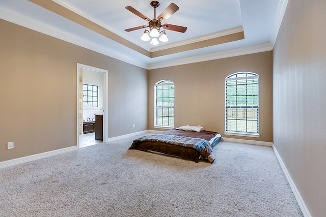 bedroom with ensuite bathroom, ornamental molding, ceiling fan, a raised ceiling, and light carpet