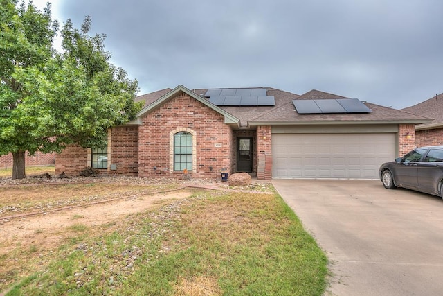 single story home featuring a garage, a front yard, and solar panels