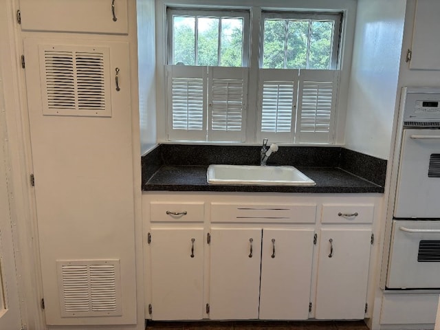 kitchen featuring white cabinetry, plenty of natural light, sink, and double oven