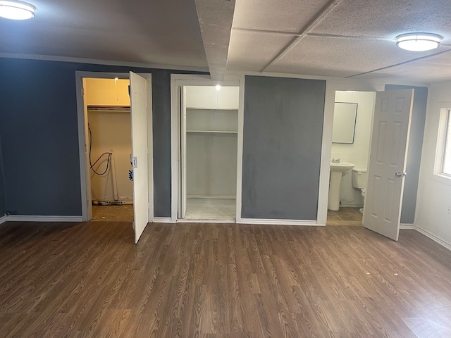 301 E Ave, Ballinger, TX 76821 - unfurnished bedroom featuring ensuite bathroom, dark hardwood / wood-style floors, sink, a walk in closet, and a closet